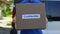 Confidential parcel courier in uniform holding cardboard box, document shipping