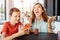 Conflict between mother and son about smartphone addiction in cafe. Mad mom and a teen playing games on mobile phone and