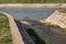 Confluence of the small to big river with rock quay on sunny spring day in city park