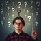 Confused adolescent guy, wearing eyeglasses gesturing index finger up, perplexed expression isolated on grey wall background.