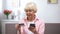 Confused aged woman with credit card and smartphone trying to pay bills online