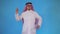 Confused arab man stands on a blue background