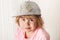 Confused Caucasian blond baby girl in gray cap