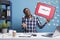 Confused and clueless company office worker holding help cardboard bubble sign while shrugging in workspace.