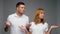 Confused couple in white t-shirts shrugging