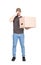 Confused delivery man, full length portrait, holding a cardboard box while keeps a hand to forehead, isolated on white. Puzzled