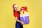 Confused delivery woman holding stack of presents and looking at camera with asking expression.