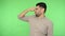 Confused disgusted brunette man pinching nose and turning from bad awful smell. green background, chroma key
