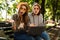 Confused displeased ladies friends outdoors sitting using laptop computer.