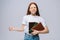 Confused displeased young woman college student holding book and screaming looking at camera