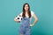 Confused displeased young woman football fan support favorite team with soccer ball isolated on blue turquoise