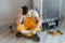 Confused handyman in yellow uniform reading manual for fridge indoors. House renovation conception