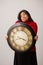 Confused Hispanic Woman Holds Clock In Front Of Her