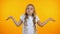 Confused kid shrugging on yellow background, lack of ideas, feeling uncertain