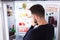 Confused Man Looking At Food In Refrigerator