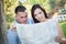 Confused Mixed Race Couple Looking Over Map Outside