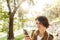 Confused pretty woman walking outdoors in park in beautiful spring day using mobile phone