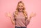 Confused screaming blonde woman in sweater with closed eyes over pink background