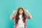 confused teen girl with curly hair point finger on crown on blue background, beauty