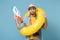 Confused traveler tourist man in yellow clothes with photo camera isolated on blue background. Passenger traveling