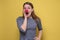 Confused woman with red clown nose over yellow background