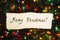 Congratulatory inscription merry Christmas on a Christmas garland on a dark background