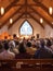 Congregation members gather in a church, attentively facing the pulpit where a sermon is delivered, the atmosphere