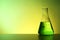 Conical flask with liquid on table against color background