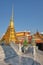 A conical gilded tower on the territory of the Temple of the Emerald Buddha on a sunny day