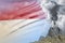 conical volcano eruption at day time with white smoke on Indonesia flag background, suffer from natural disaster and volcanic