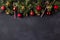 Coniferous Christmas garland decorated with red balls and golden bells with caramel canes at the top of the black table