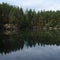 Coniferous forest is reflected in a lake with granite shores