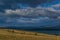 Coniferous green trees and road in yellow grassy coast of blue lake Baikal with mountains. Summer landscape in sunset