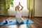 Conscious pregnant woman practicing prenatal stretching exercises and pregnancy yoga in hero pose on blue exercise mat