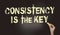 Consistency is the Key chalkboard with text and hand holding piece of cahlk. Business success concept