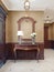 Console key table with mirror in wooden frame and table lamp. Classic hallway interior with patterned yellow wallpaper and brown