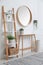 Console table with shelving unit and mirror on white wall in hallway. Interior design