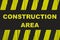 Construction area warning sign with yellow and black stripes painted over cracked wood.