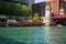 Construction barge floats next to skyscraper while kayak and motorboat move past on Chicago River