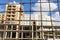 Construction building unfocused silhouette shape behind rusty sharp fence foreground