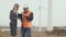 Construction business. The contractor in a reflective vest and helmet works with a business woman with a digital tablet