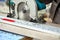 A construction contractor worker using a worm-driven hand-held circular saw to cut boards and plastic. Construction