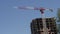 A construction crane on a blue sky background.A red and white lifting tower crane builds a building. Real estate under constructio