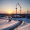 Construction crane silhouette in the sunset with snowy winter landscape.