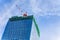 Construction crane on top of tower working to build high skycrapper office building in the development city, cloud blue sky