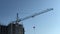 Construction crane turns the arrow on the background of construction and the sky