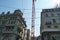 A construction crane among two historical building in Zurich, Bahnhofstrasse, on one of therm there is Glockenspiel, playing bells