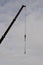 Construction cranes with arrow structure and hook pointing up against cloudy sky