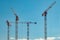 Construction cranes work on creation site against sky background