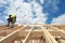 Construction crew working on the roof against blue sky.